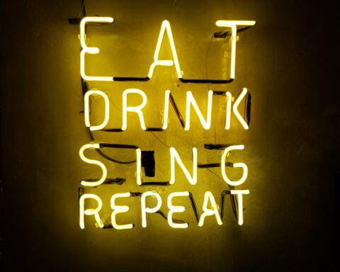 turned on eat drink sing repeat neon signage on wall