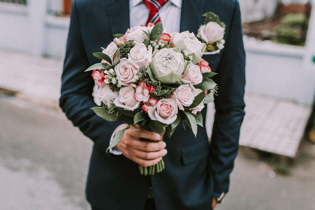 person in suit and tie holding bouquet