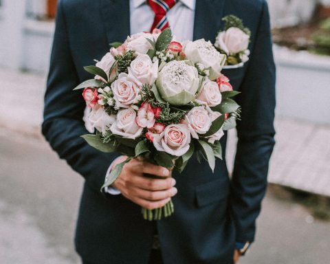 person in suit and tie holding bouquet