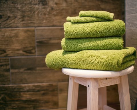 folded green towels on a stool in a sauna