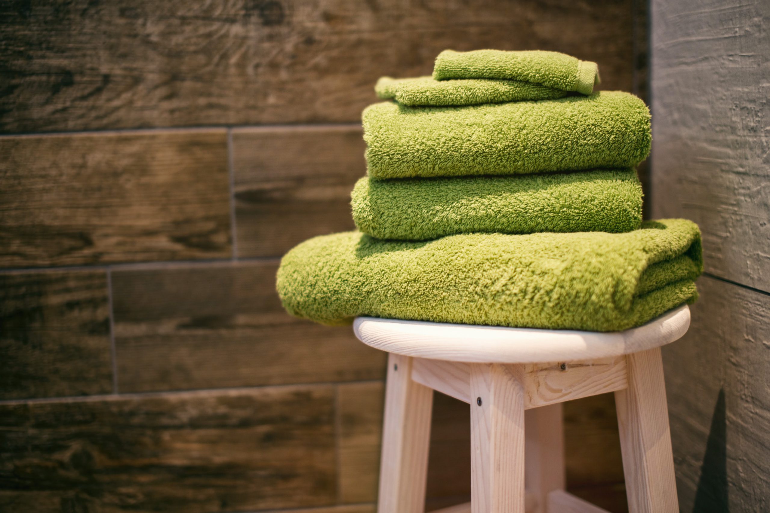 folded green towels on a stool in a sauna