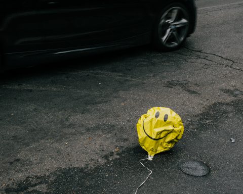 yellow smiley balloon, deflated and on the street