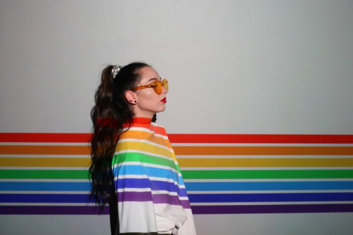 rainbow shines on person turned to the right against a white wall