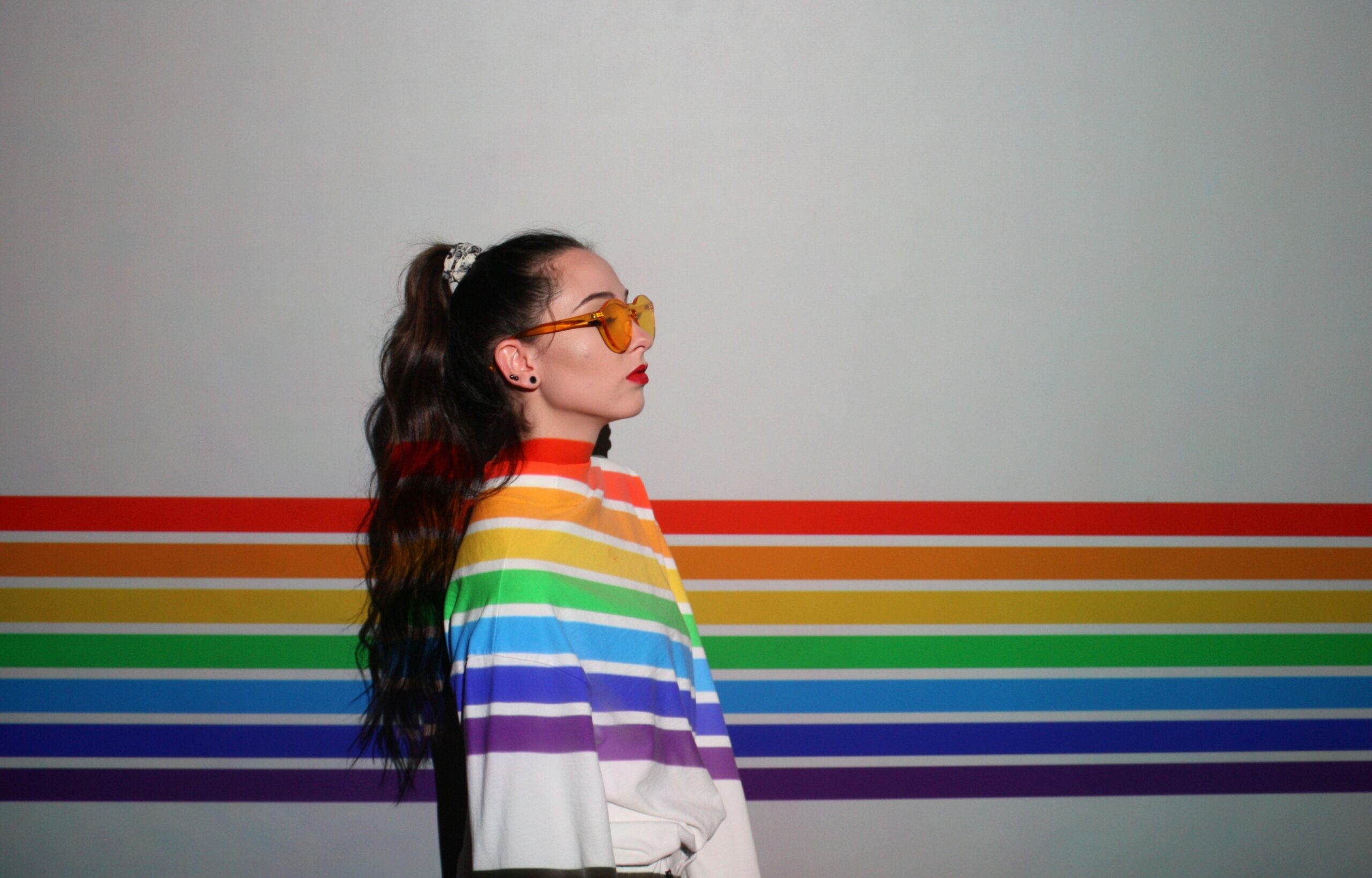 rainbow shines on person turned to the right against a white wall