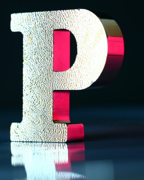 a sculpture of the letter p on a mirrored surface and under a red light